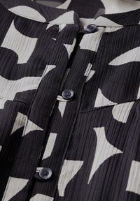 Černá a smetanová tkanina s vzorem a crinkle texturou, disponující zapínáním na knoflík a límečkovým výstřihem.