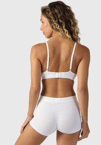 Soutien-gorge en coton blanc avec bretelles ajustables et fermeture à crochets, associé à un short en coton blanc avec une taille douce et un design minimaliste.