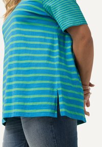 Top de manga corta con rayas horizontales azules y verdes, fabricado en un tejido suave, con aberturas laterales y un corte relajado.