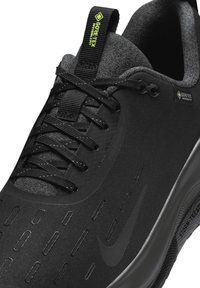 Czarne buty sportowe z teksturowaną cholewką, refleksyjnymi akcentami i widoczną marką. Posiadają metkę Gore-Tex oraz str streamlined design dla trwałości.