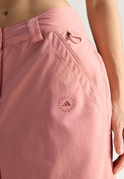 Růžové šortky z lehké látky, s nášivkou s logem, bočními kapsami a stahováním v pase. Hladká textura.