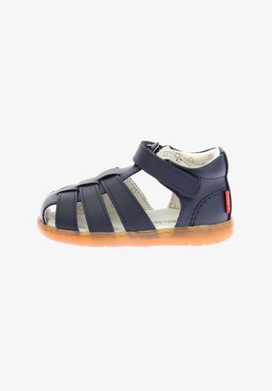 Sandalia de cuero azul marino con múltiples correas, diseño de punta abierta y cierre de velcro. Cuenta con una suela de goma color marrón y un forro interior estampado.