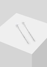 Boucles d'oreilles en argent avec un design mince et allongé, accentuées de chaînes et de barres. La surface est lisse avec une finition polie.