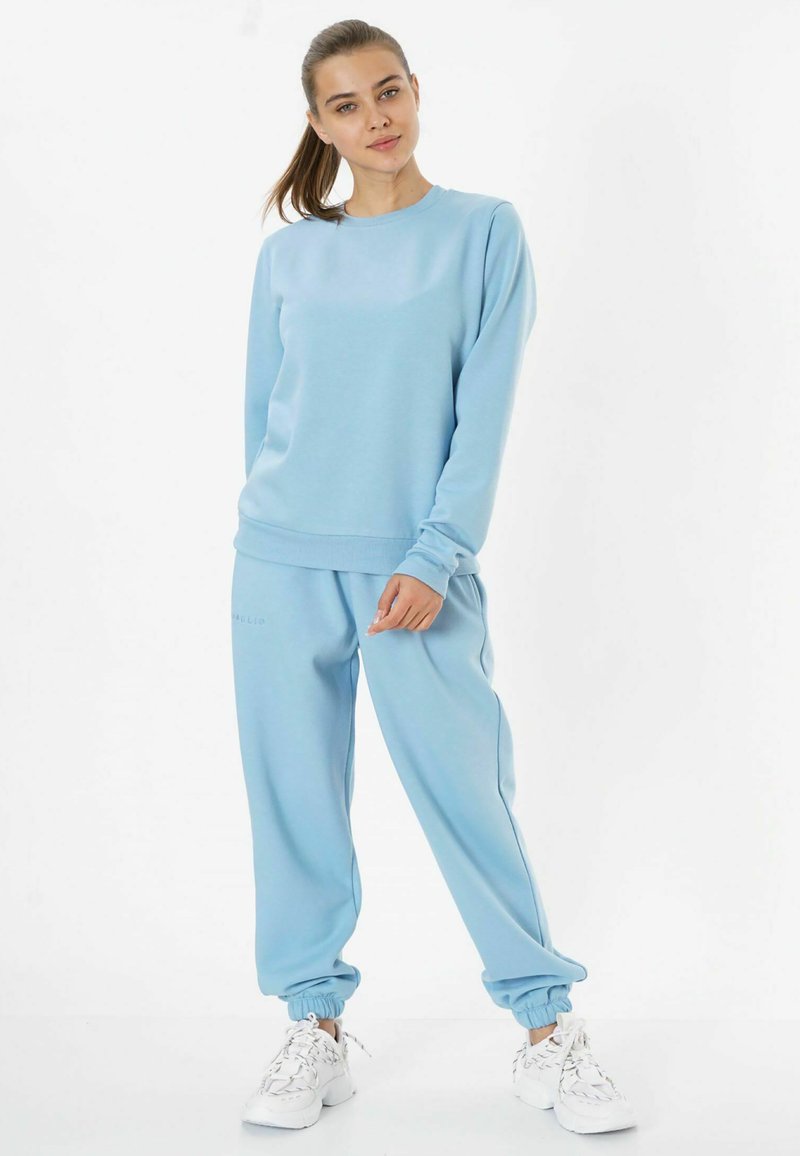 Helles blaues Sweatshirt mit rundem Halsausschnitt und lockerer Passform, kombiniert mit passenden hellblauen Jogginghosen mit elastischen Bündchen.