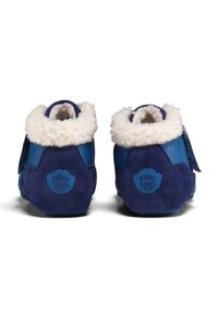 Scarpine azzurre per bambini con esterno in camoscio, rivestimento interno bianco soffice e cinturino in Velcro. Presenta un logo circolare sul tallone in blu a contrasto.