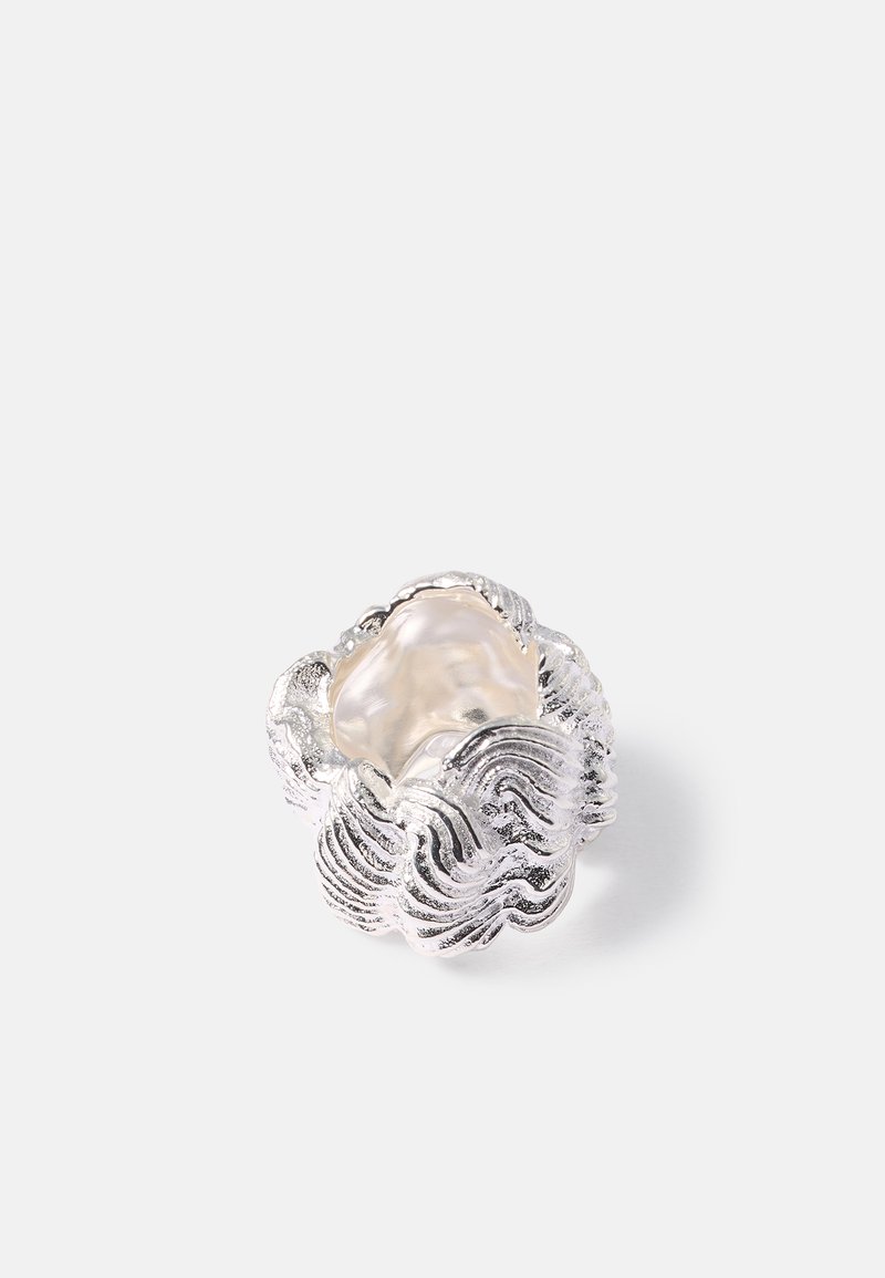 Δαχτυλίδι σε ασημί τόνο που έχει σχήμα σύννεφου, με κυματιστά σχέδια και κεντρική διαφανή πέτρα, διαθέτοντας υφή και οργανική μορφή.
