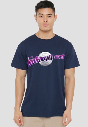 Navy blue cotton t-shirt featuring "Galaxy Quest" in purple and silver text with a circular graphic at the center. Short sleeves and round neck.