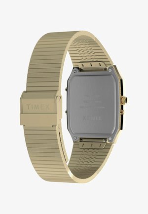 Montre-bracelet dorée avec un boîtier rectangulaire, un bracelet en métal nervuré et un fond en acier inoxydable brossé. Comprend une couronne ronde pour les réglages.
