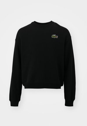 Schwarzes, gekürztes Sweatshirt aus Baumwollmischung mit langen Ärmeln und einem gestickten, grünen Krokodil-Logo auf der Brust.