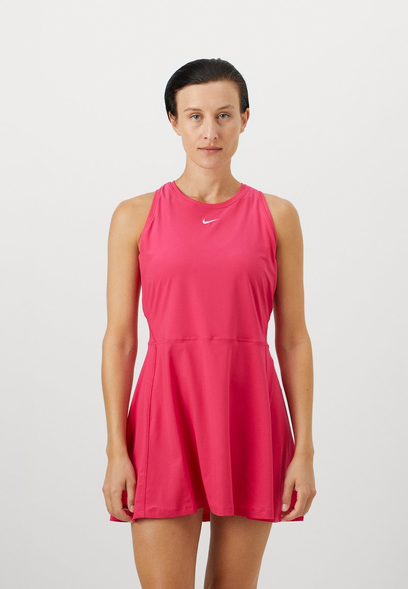 Ružové športové šaty s okrúhlym výstrihom a bez rukávov, majú volánovú sukňu a malé biele logo Nike na hrudi.