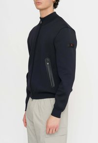 Giacca bomber blu navy con zip, colletto alto, due tasche laterali, tessuto strutturato e una toppa con logo sulla manica. Design semplice e moderno.