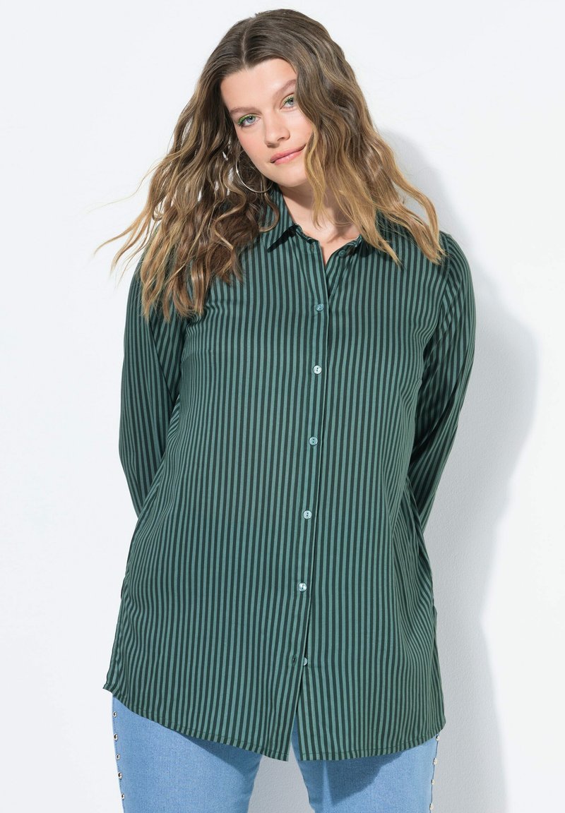 Camicia a maniche lunghe a righe verdi con bottoni in un tessuto liscio, orlo curvo e bottoni azzurri. Presenta righe verticali e un colletto classico.