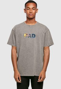 Grijze oversized katoenen T-shirt met een "DAD" grafisch ontwerp in gradient kleuren. Korte mouwen en een ronde halslijn met een casual pasvorm.