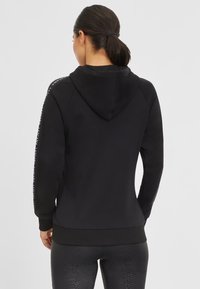 Black hooded sweatshirt with ribbed cuffs and hem. Features logo accents on sleeves. Soft fabric, fitted design for comfort.