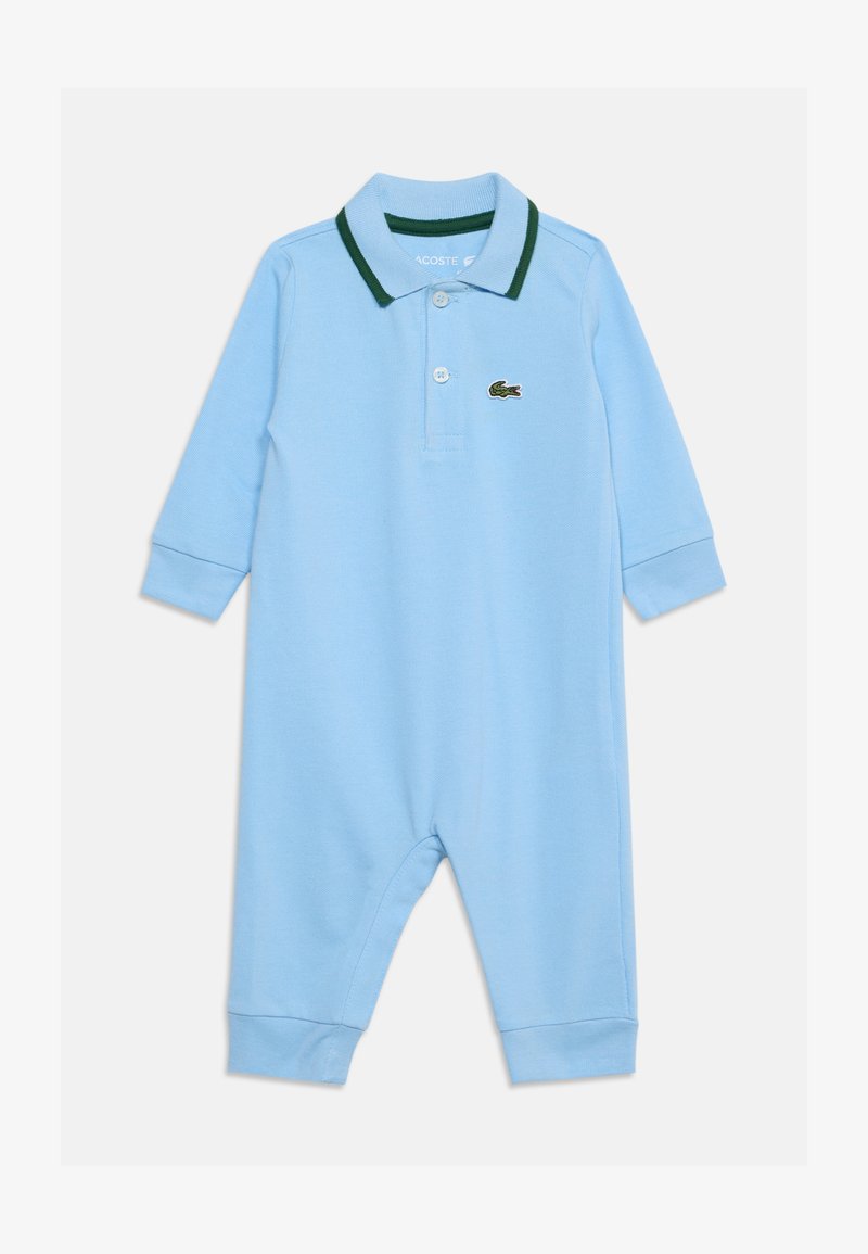 Barboteuse bébé bleu clair à manches longues, avec col polo bordé de vert et deux boutons, arborant un petit logo crocodile vert sur la poitrine.