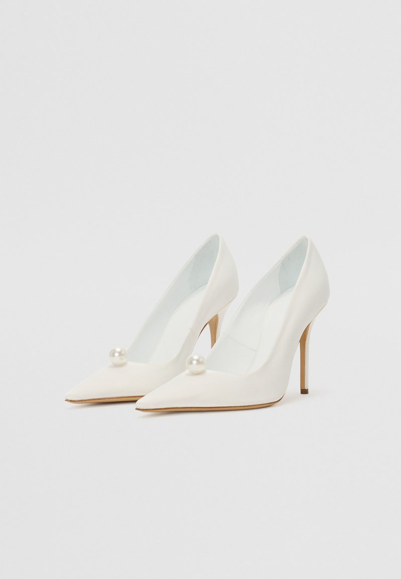 Weiße Pumps mit hohen Absätzen und spitzem Zehendesign, verziert mit einem Perlenakzent am Vorderblatt und einem schlanken Stiletto-Absatz. Glatte Textur.