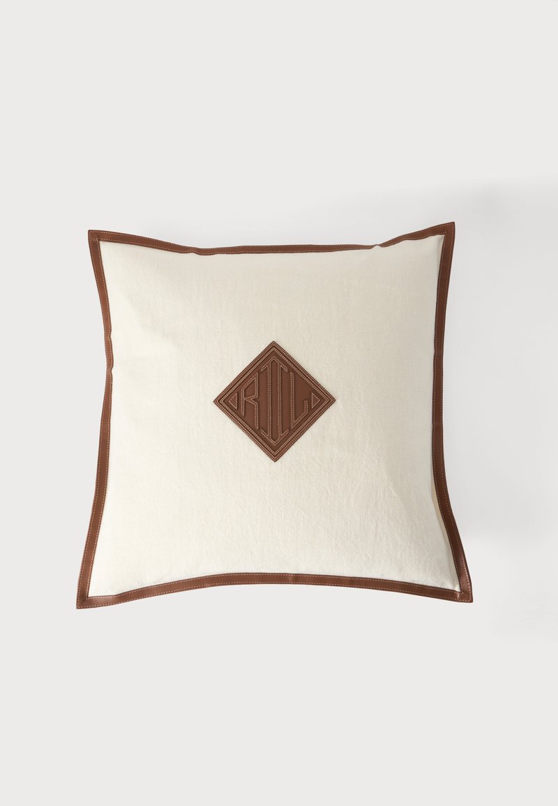 Coussin carré blanc avec bordure en cuir marron et un patch en cuir marron en forme de losange brodé au centre.
