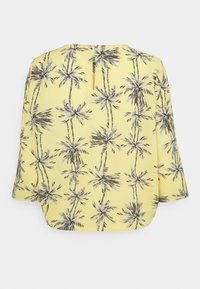 Blusa gialla con motivo a palma in nero e grigio. Vestibilità ampia con maniche a tre quarti e uno spacco nella parte posteriore del collo.