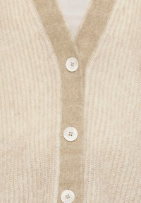 Cremfarbener Cardigan mit geripptem Muster, V-Ausschnitt-Design und fünf großen, runden Knöpfen in heller Farbe.