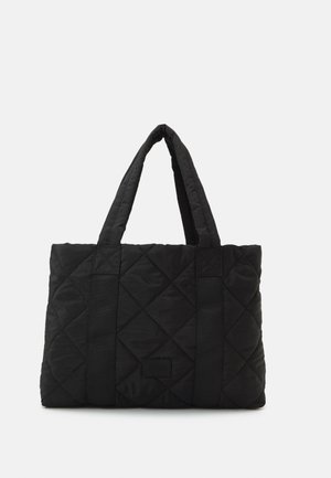 Bolso tote negro acolchado con dos asas acolchadas y un patrón sutil de costuras cuadradas sobre fondo liso.