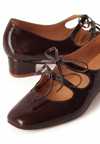 Donkerbruine lakleren Mary Jane schoenen met lage blokhakken en strikbandjes over de wreef, met een afgeronde vierkante neus ontwerp.