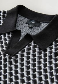 Black and grey patterned polo shirt with a textured design, ribbed collar, and label showing size M and brand name "NEXT."