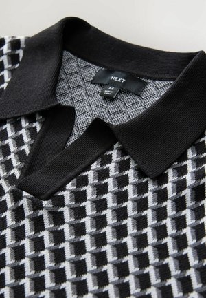 Črno-siva polo majica s patternom z teksturiranim dizajnom, rebrastim ovratnikom in oznako, ki prikazuje velikost M in ime blagovne znamke "NEXT."