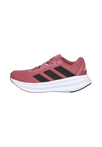 Zapatillas deportivas en rosa claro, con una parte superior de malla texturizada, tres rayas negras, una entresuela blanca acolchada y acentos en negro en la suela.