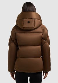 Giacca a giacca marrone con colletto alto, caratterizzata da un ampio cappuccio e design trapuntato. Include un dettaglio con bottone nero e polsini elasticizzati.