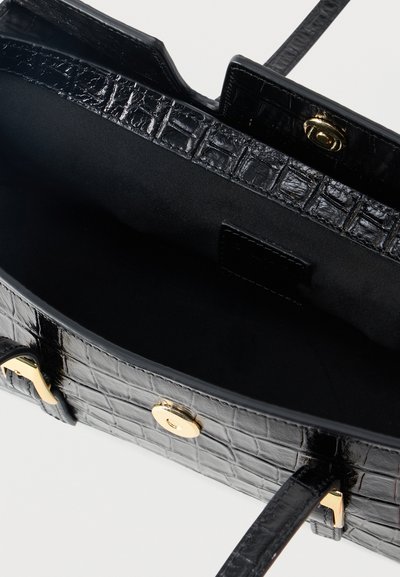 Μαύρη τσάντα χειρός με υφή εμπνευσμένη από κροκόδειλο, χρυσό κούμπωμα, ανοιχτό πάνω μέρος που αποκαλύπτει ευρύχωρο μαύρο εσωτερικό και δύο λαβές.