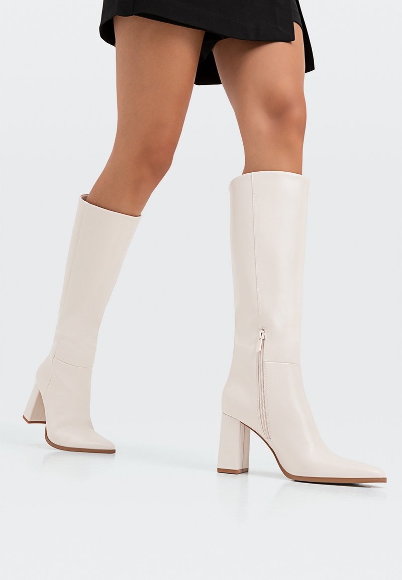 Stiefeletten bis zum Knie mit Absatz aus glattem, hellbeigem Leder. Quadratzehenform mit seitlichem Reißverschluss und Blockabsatz, ausgestattet mit einem nahtlosen Design.