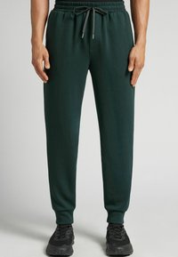 Groene sweatpants van zacht materiaal, met een elastische tailleband met trekkoorden, taps toelopende pijpen en ribgebreide boorden.