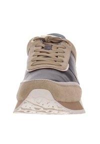 Vue de face d'une sneaker beige et grise avec des lacets noués en nœud, fabriquée en matériaux suédés et textiles et dotée d'une semelle blanche texturée.