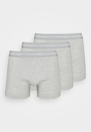 Drei Paare hellgrauer Baumwoll-Boxershorts mit glatter Textur und einem weichen elastischen Bund, der das "Calvin Klein"-Logo trägt.