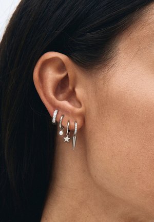 Pendientes de plata con diseños diversos: tres aros adornados con gemas transparentes, un colgante de perla, una estrella y un detalle en forma de punta afilada.