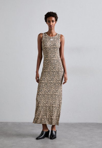 Abito maxi senza maniche, con stampa leopardata in tessuto beige e nero, caratterizzato da una silhouette elegante e una texture morbida, abbinato a tacchi neri.