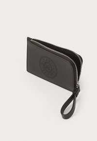 Portafoglio in pelle nera con logo testurizzato, chiusura con zip e tracolla. Presenta una finitura liscia e una forma arrotondata.