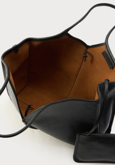 Czarna skórzana torba na ramię o miękkiej, teksturowanej powierzchni, jasnobrązowe wnętrze, przestronny design oraz mała kieszonka na zamek przymocowana wewnątrz.