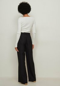 Witte geribde lange mouwen top gecombineerd met hoge taille zwarte wijde broek, met een soepele textuur en een op maat ontworpen stijl.