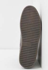 Semelle de chaussure grise avec une texture à rainures, marquée de la taille "37." Matériau en caoutchouc solide, présentant un design plat et arrondi sans accents.