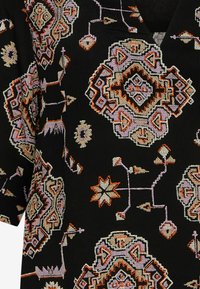 Tessuto nero con intricati motivi geometrici in arancione, rosa e crema, caratterizzato da una superficie testurizzata e maniche corte.
