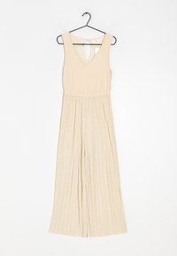 Jumpsuit beige sin mangas con escote en V y espalda con abertura. El material presenta pliegues verticales, diseño fluido y perneras anchas.