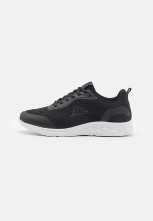 Schwarzer Sportschuh mit Mesh-Obermaterial, schwarzen Schnürsenkeln und weißer strukturierter Sohle, seitlich auf hellem einfarbigem Hintergrund gesehen.