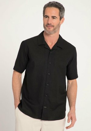 Chemise noire à manches courtes en tissu avec une finition texturée. Dotée d'un col pointu, de boutons sur le devant et d'un petit logo brodé sur la poitrine.