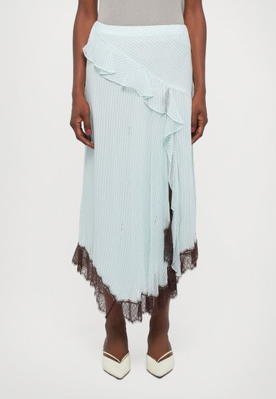 Falda maxi a rayas azul claro con dobladillo con volantes y borde de encaje, con un corte asimétrico. Combinada con tacones blancos de punta.