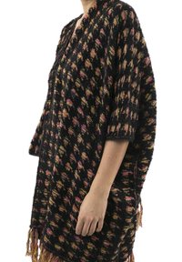 Černý a vícebarevný pončo s vzorem a třásněmi na lemu, s volným střihem a krátkými rukávy, vyrobené z texturované látky.