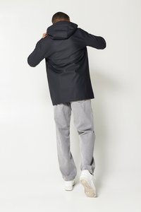 Black hooded jacket with a smooth texture, relaxed fit, and a front pocket, paired with light gray pants and white sneakers.