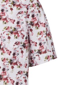 Camicia di tessuto con motivo floreale e maniche corte. Presenta grandi fiori rossi, rosa e verdi su uno sfondo bianco. Include una tasca applicata.