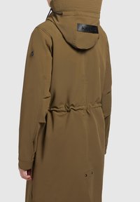 Brown, long parka jacket with a hood, featuring a cinched waist, ribbed details, and a black logo patch on the back.