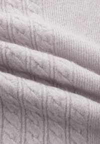 Tissu tricoté léger de couleur violette avec une texture côtelée et un motif en torsades. Texture douce et duveteuse avec un aspect superposé.